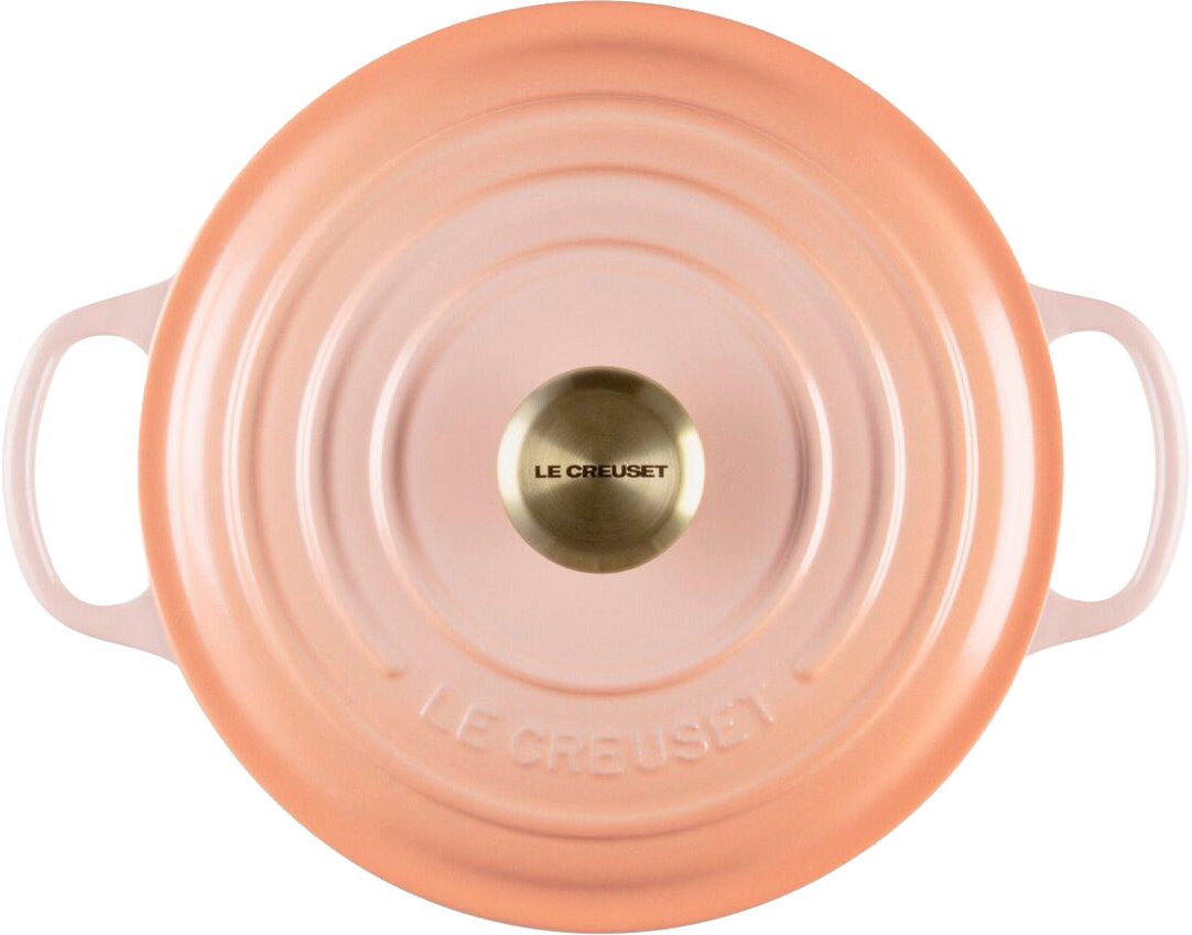 Runder Le Creuset Gusseisentopf mit Deckel in zartem Rosa/Apricot, mit zwei seitlichen Griffen und goldfarbenem Knauf, Draufsicht von oben