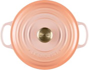Runder Le Creuset Gusseisentopf mit Deckel in zartem Rosa/Apricot, mit zwei seitlichen Griffen und goldfarbenem Knauf, Draufsicht von oben
