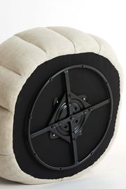 Unterseite eines Sessels mit drehbarem Mechanismus, beige gepolstert, aus der Perspektive von unten.