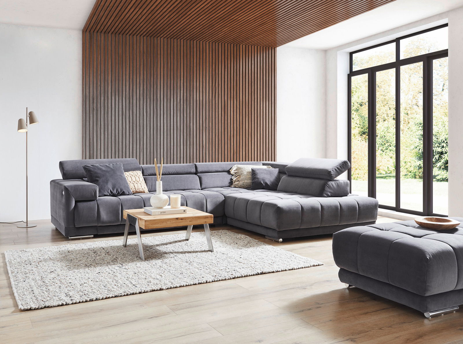 Ecksofa in modernem Wohnzimmer mit Holzverkleidung und großen Fenstern, Perspektive von vorne links