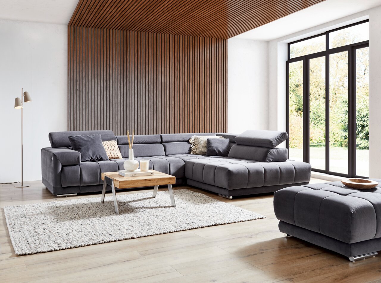 Ecksofa in modernem Wohnzimmer mit Holzverkleidung und großen Fenstern, Perspektive von vorne links