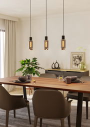 Drei moderne Pendelleuchten MAIONE hängen über einem Esstisch in einem stilvoll eingerichteten Raum, seitliche Perspektive.
