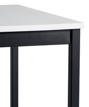 Close-up van een moderne eettafel met een wit tafelblad en een zwart metalen onderstel, gezien vanaf de zijkant