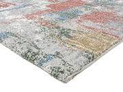 Nahaufnahme eines bunten Frisé-Teppichs mit abstraktem Muster in Rot, Blau, Grün und Beige, aus seitlicher Perspektive fotografiert.