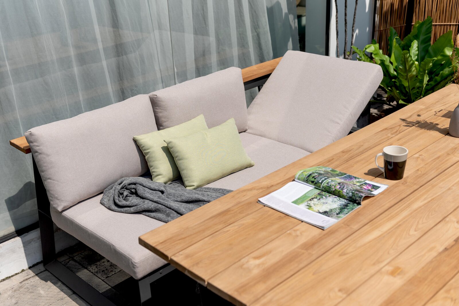 Gartenset mit beigem Sofa und Holztisch, seitliche Perspektive