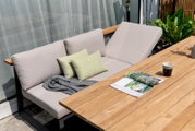 Gartenset mit beigem Sofa und Holztisch, seitliche Perspektive
