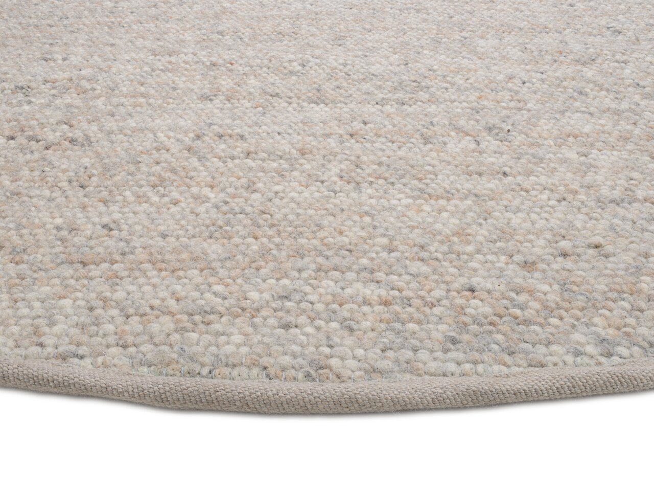 Nahaufnahme eines handgewebten Teppichs mit strukturierter Oberfläche in neutralen Farbtönen, von der Seite fotografiert.