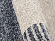 Nahaufnahme eines Frisé-Teppichs mit grauen und cremefarbenen Streifen, seitliche Perspektive