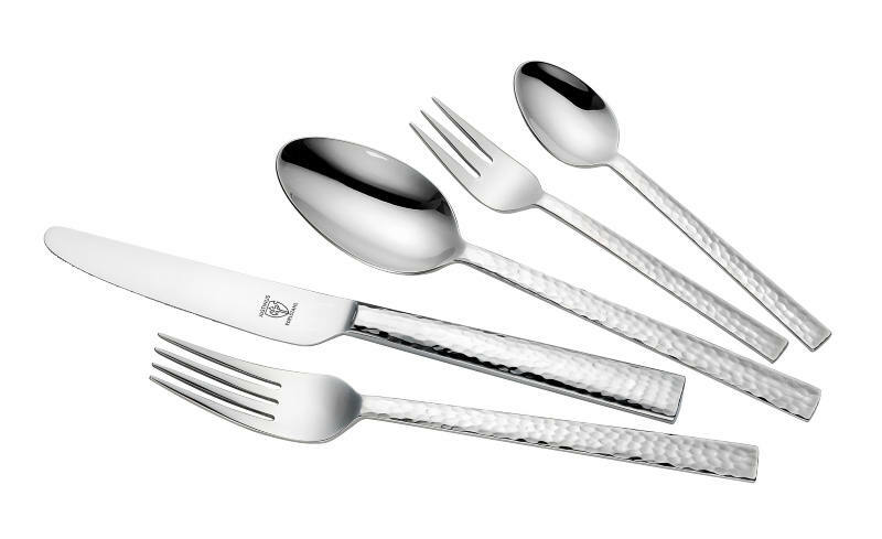 Set aus glänzendem Besteck mit gehämmerter Oberfläche, bestehend aus Messer, Gabel, Löffel, Dessertgabel und Teelöffel, in schräger Draufsicht.
