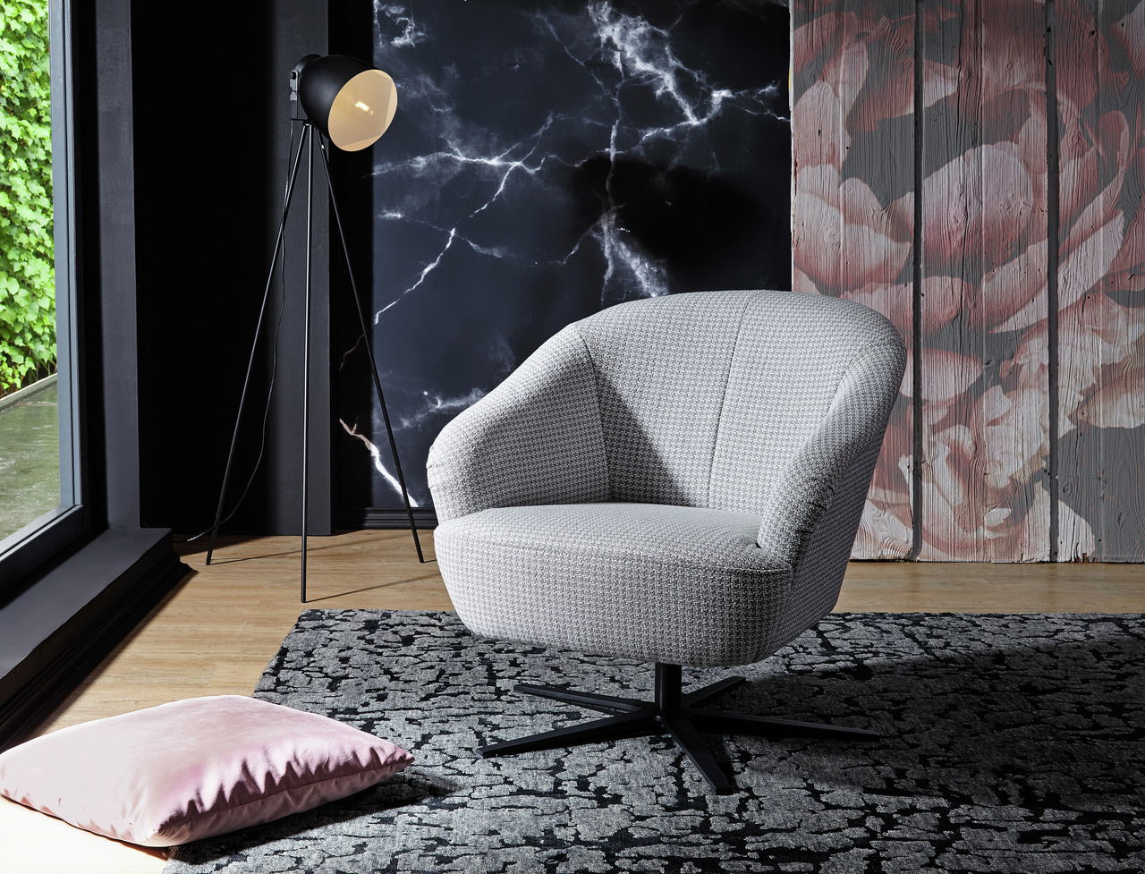 Moderner grauer Drehsessel in einem stilvoll eingerichteten Raum, seitliche Perspektive.