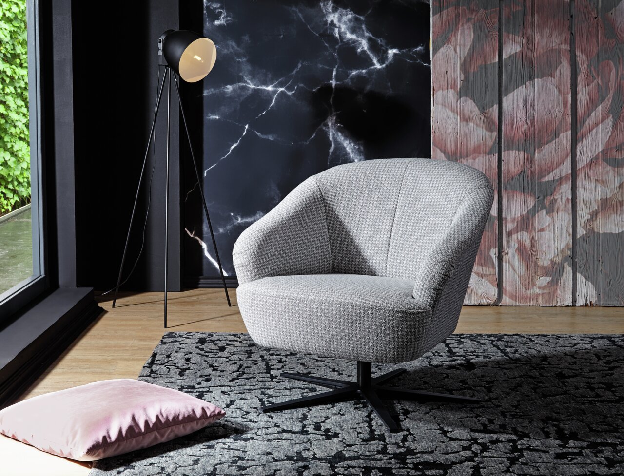 Moderner grauer Drehsessel in einem stilvoll eingerichteten Raum, seitliche Perspektive.