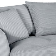 Nahaufnahme einer grauen Rundecke mit geripptem Stoff und mehreren Kissen.