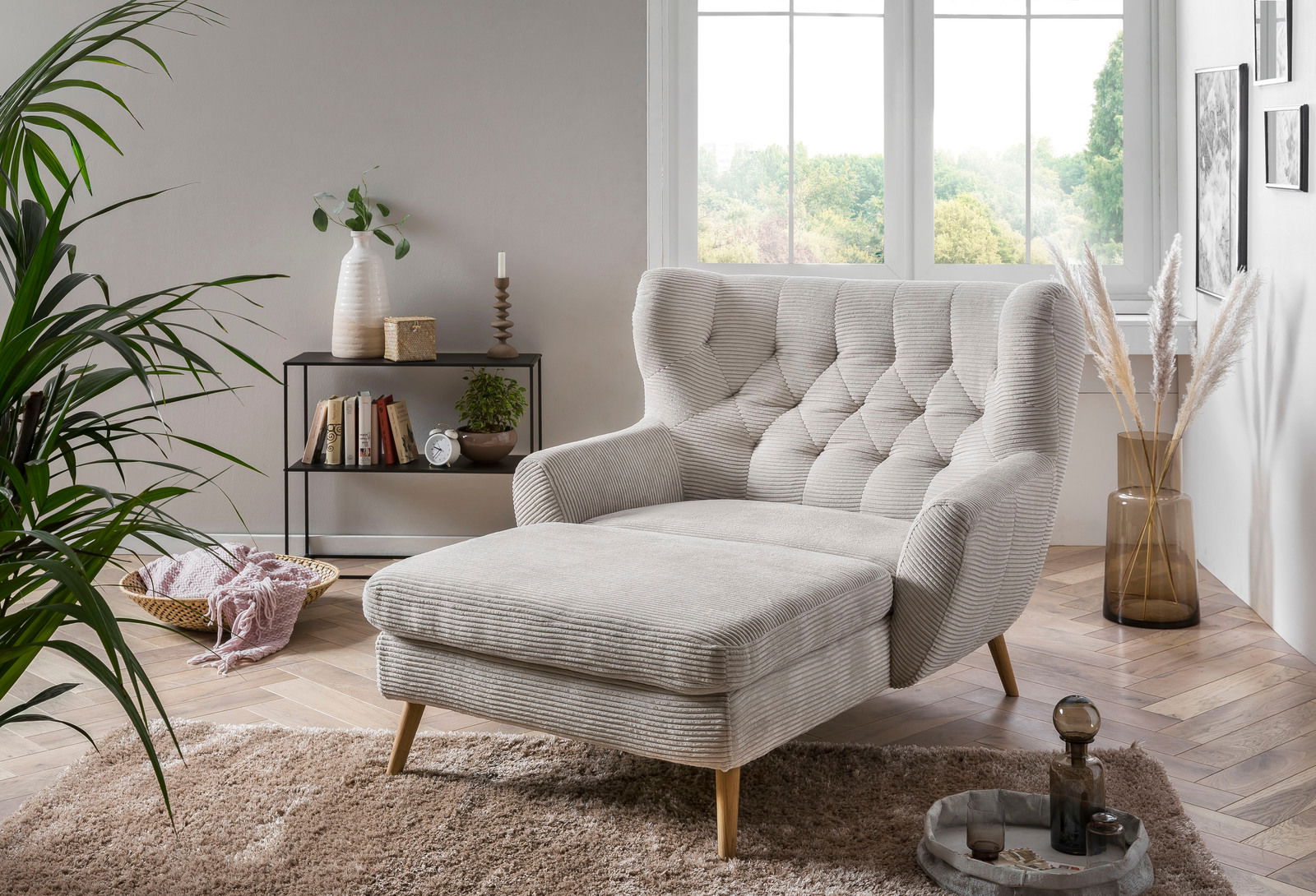 Gemütlicher Big Sessel in einem modernen Wohnzimmer, seitliche Perspektive, mit hellgrauem Stoff und Holzbeinen, umgeben von Pflanzen und Dekorationen.