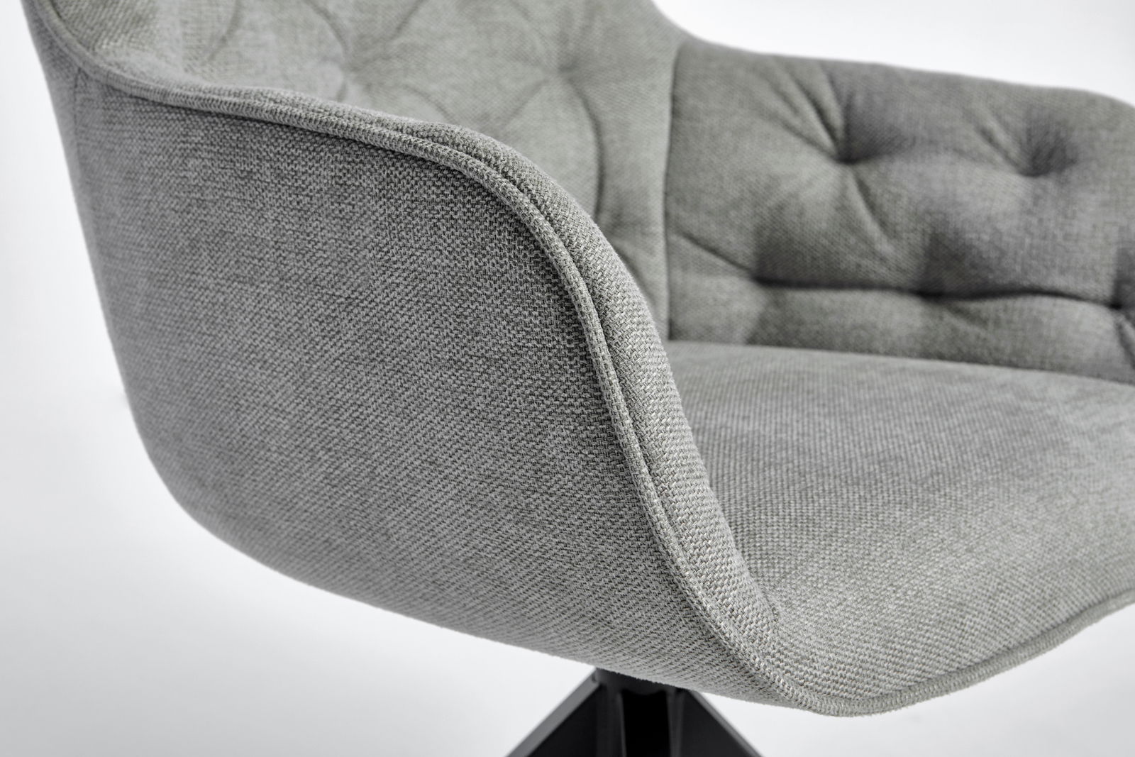 Nahaufnahme eines grauen, gepolsterten Stuhls mit Armlehne und gesteppter Rückenlehne, seitliche Perspektive.