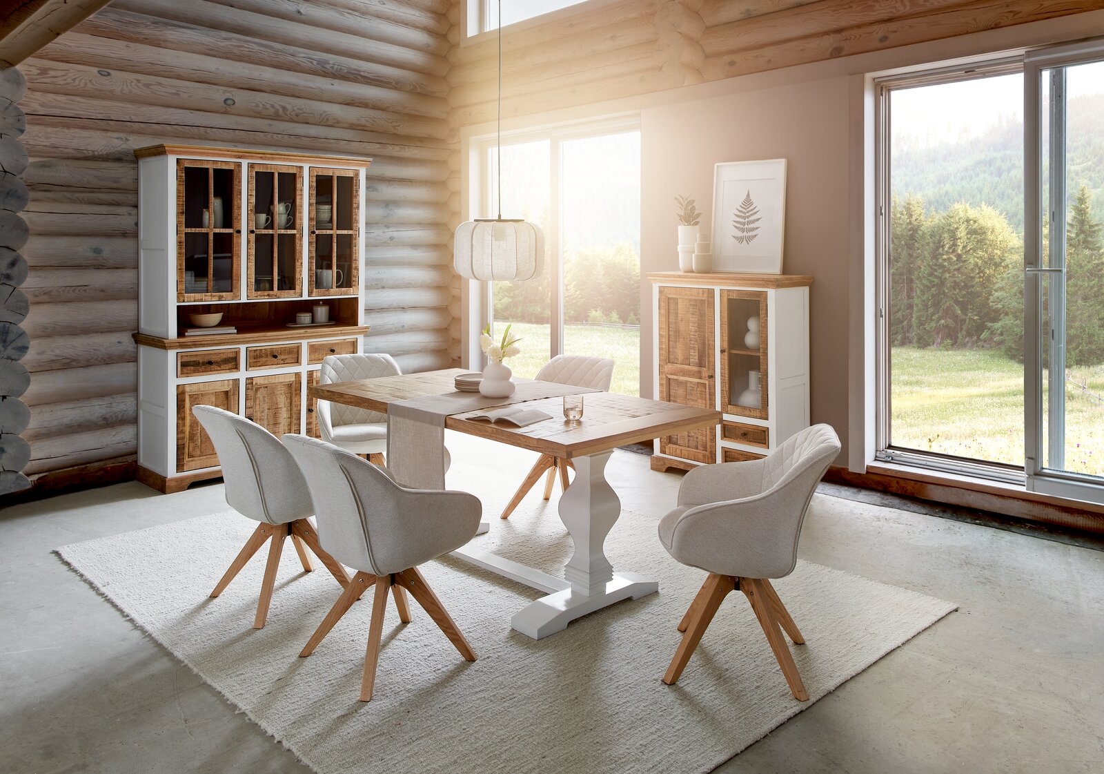 Esszimmer mit Esstisch aus Holz und weißen Stühlen, umgeben von Vitrinenschränken und einem großen Fenster mit Blick auf die Natur. Perspektive von vorne.