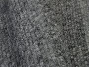 Nahaufnahme eines grauen Handweb Teppichs mit strukturierter Oberfläche in diagonaler Perspektive.