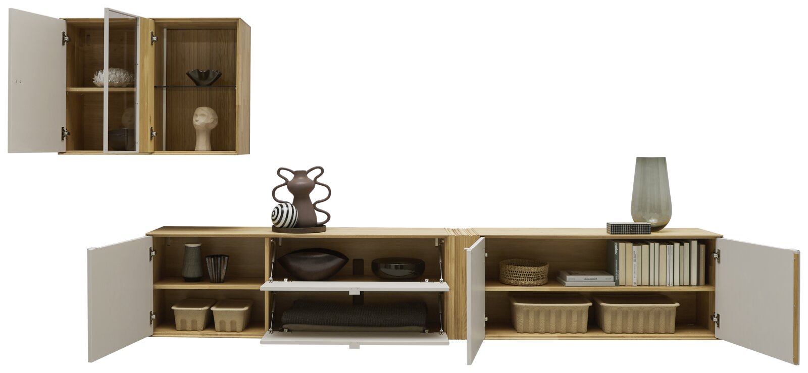 Modernes, niedriges Sideboard aus Holz mit weißen Türen und Klappfächern, mehrere Fächer geöffnet und mit Deko, Körben und Büchern bestückt; Ansicht von vorne in leichter Draufsicht.