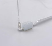 Nahaufnahme aus seitlicher Perspektive auf eine transparente Acrylglas-Platte mit milchig-weißem, selbstklebendem Silikon-Puffer/Abstandshalter an der unteren Ecke vor hellem Hintergrund