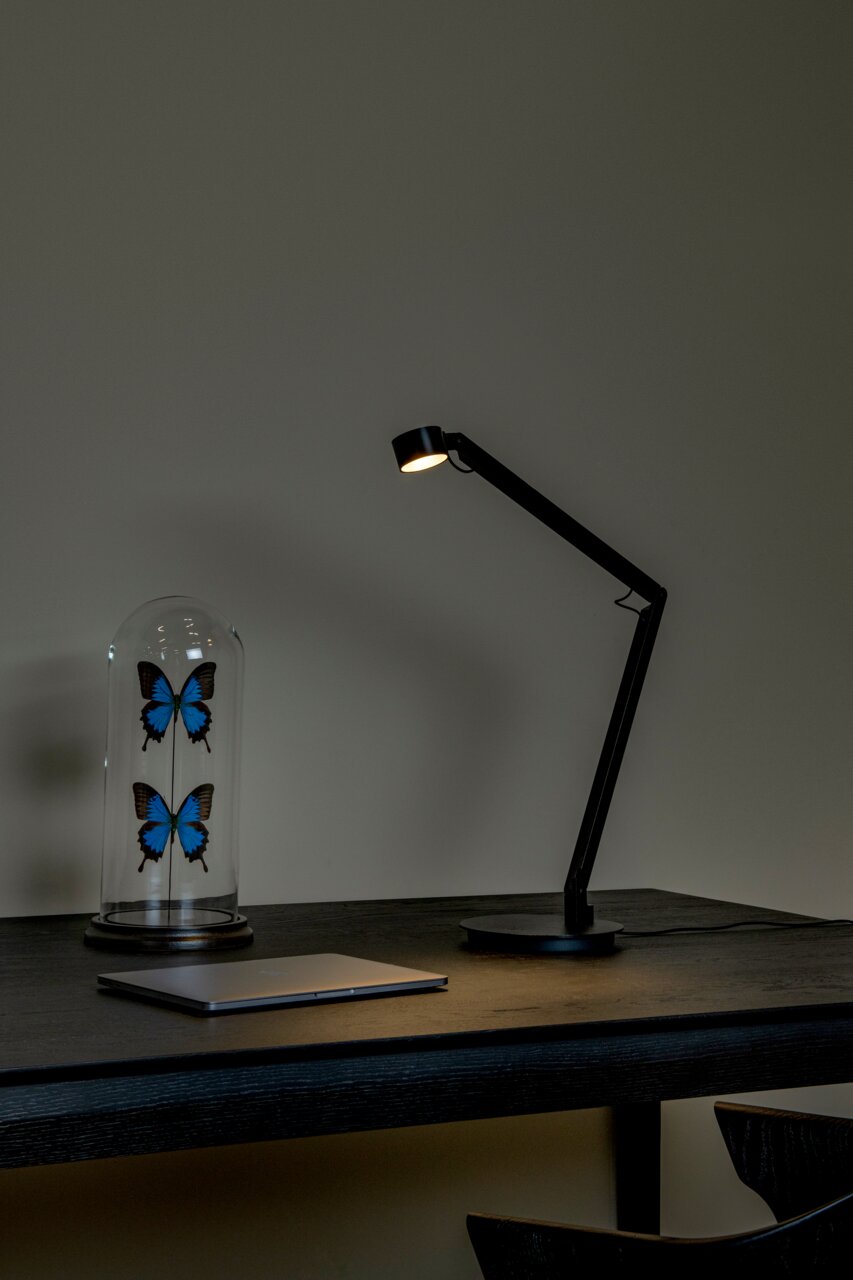 Moderne Tischleuchte in schwarzem Design auf einem Schreibtisch, seitliche Perspektive