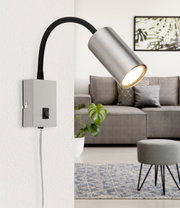 Moderne wandlamp van mat nikkel met flexibele arm, zijaanzicht, bevestigd aan een witte muur in een stijlvolle woonkamer.