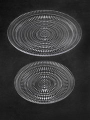 Zwei gläserne Teller mit einem detaillierten, ethnischen Muster, von oben betrachtet.