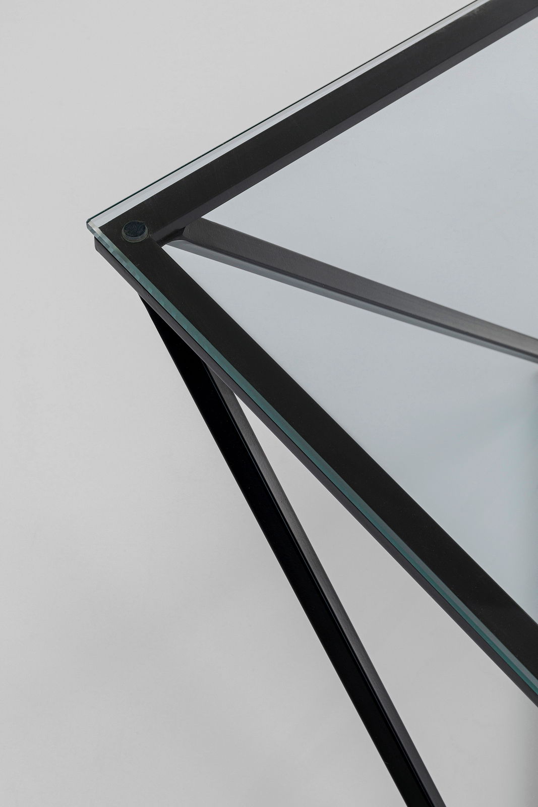 Nahaufnahme eines modernen Beistelltisches mit Glasplatte und schwarzem Metallrahmen, aus der Vogelperspektive fotografiert.