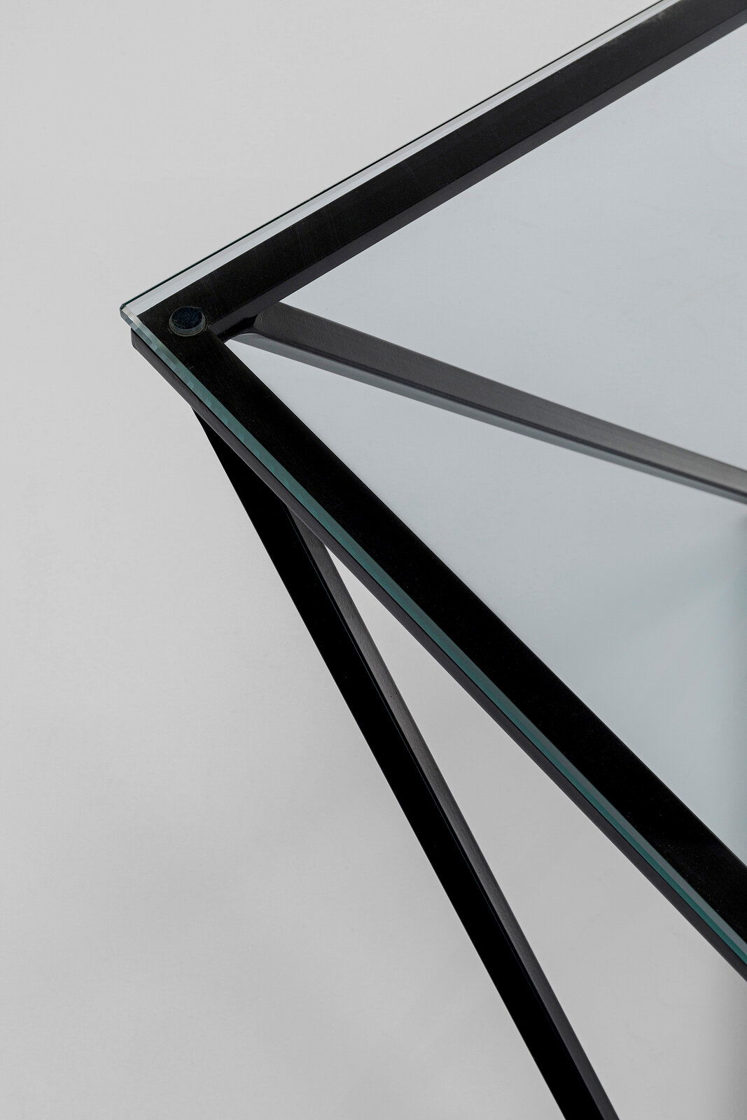 Nahaufnahme eines modernen Beistelltisches mit Glasplatte und schwarzem Metallrahmen, aus der Vogelperspektive fotografiert.