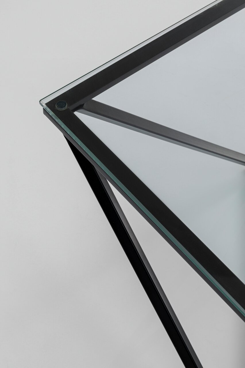 Nahaufnahme eines modernen Beistelltisches mit Glasplatte und schwarzem Metallrahmen, aus der Vogelperspektive fotografiert.