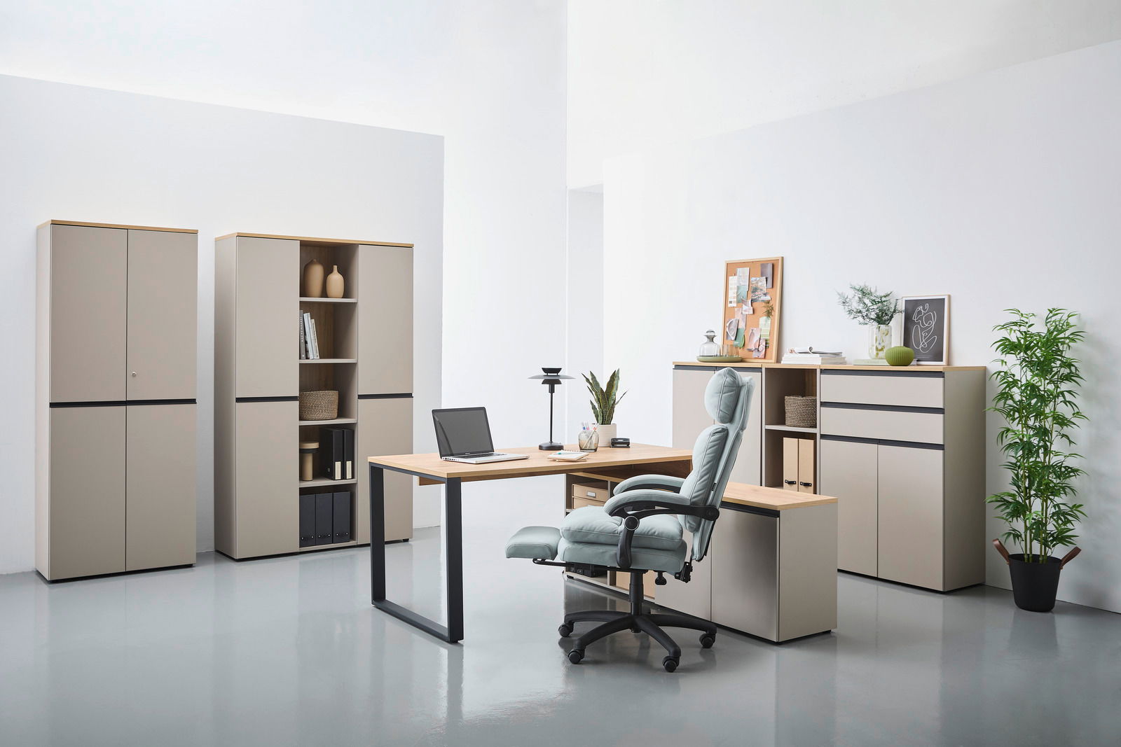 Novel Winkelschreibtisch DELTONA Moderne Büromöbel in einem hellen Raum, bestehend aus einem Winkelschreibtisch mit Laptop, einem ergonomischen Bürostuhl und mehreren Aktenschränken. Perspektive von vorne.