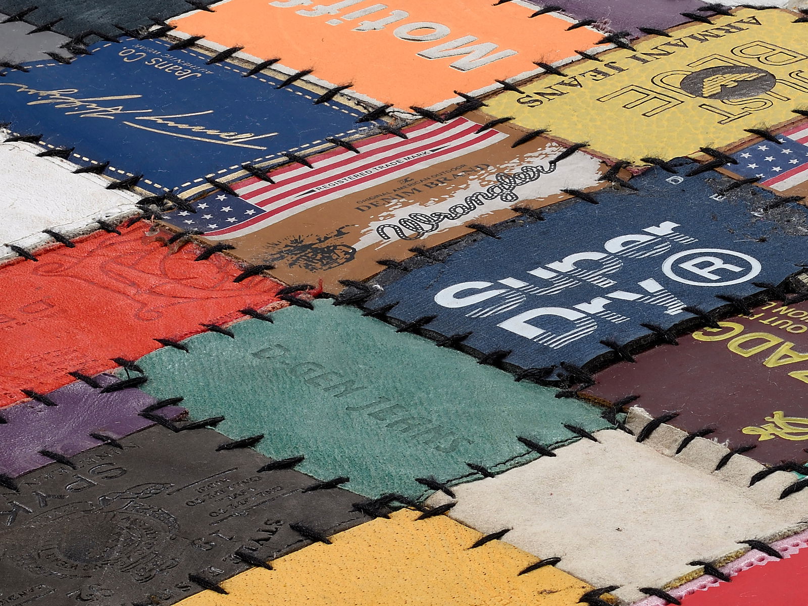 Nahaufnahme eines Lederteppichs aus verschiedenen bunten Lederetiketten, die in einem Patchwork-Muster zusammengenäht sind.