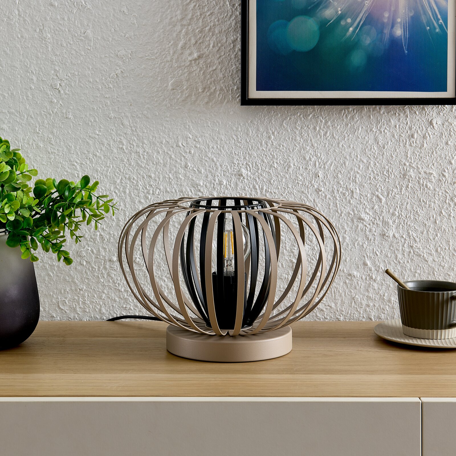 Moderne tafellamp met een bolvormig, open ontwerp van metalen spanten, gezien vanaf de zijkant.