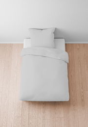 Bettwäsche-Set in Weiß auf einem Bett, von oben fotografiert, auf einem Holzboden.