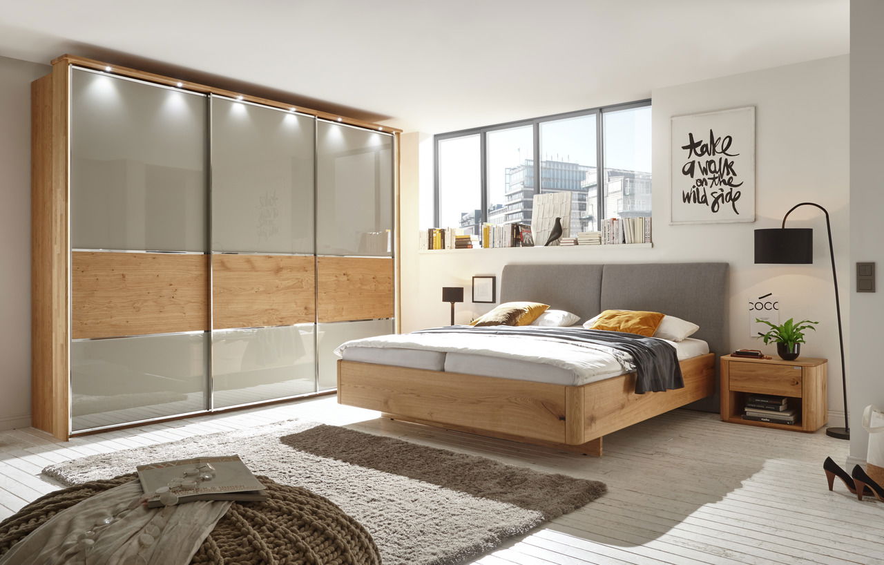 Modernes Schlafzimmer mit Holzbett, grauem Kopfteil und passender Nachtkonsole, seitliche Perspektive