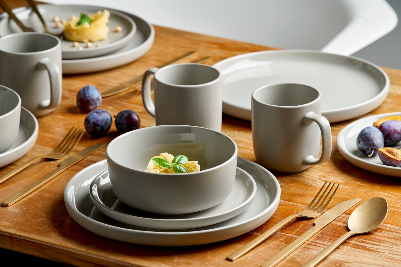 Kombiservice 16-tlg. Linz in moderner, minimalistischer Gestaltung auf einem Holztisch, mit goldfarbenem Besteck und frischen Früchten, aus der Vogelperspektive fotografiert.