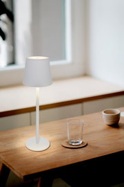 Moderne Akku-Tischleuchte in minimalistischem Design auf einem Holztisch, seitliche Perspektive