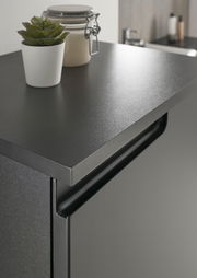 Nahaufnahme eines modernen, schwarzen Highboards mit einer dekorativen Pflanze und einem Glasbehälter auf der Oberseite, seitliche Perspektive.