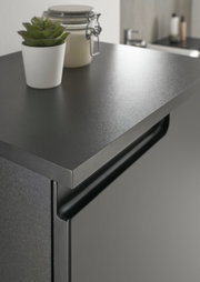 Nahaufnahme eines modernen, schwarzen Highboards mit einer dekorativen Pflanze und einem Glasbehälter auf der Oberseite, seitliche Perspektive.