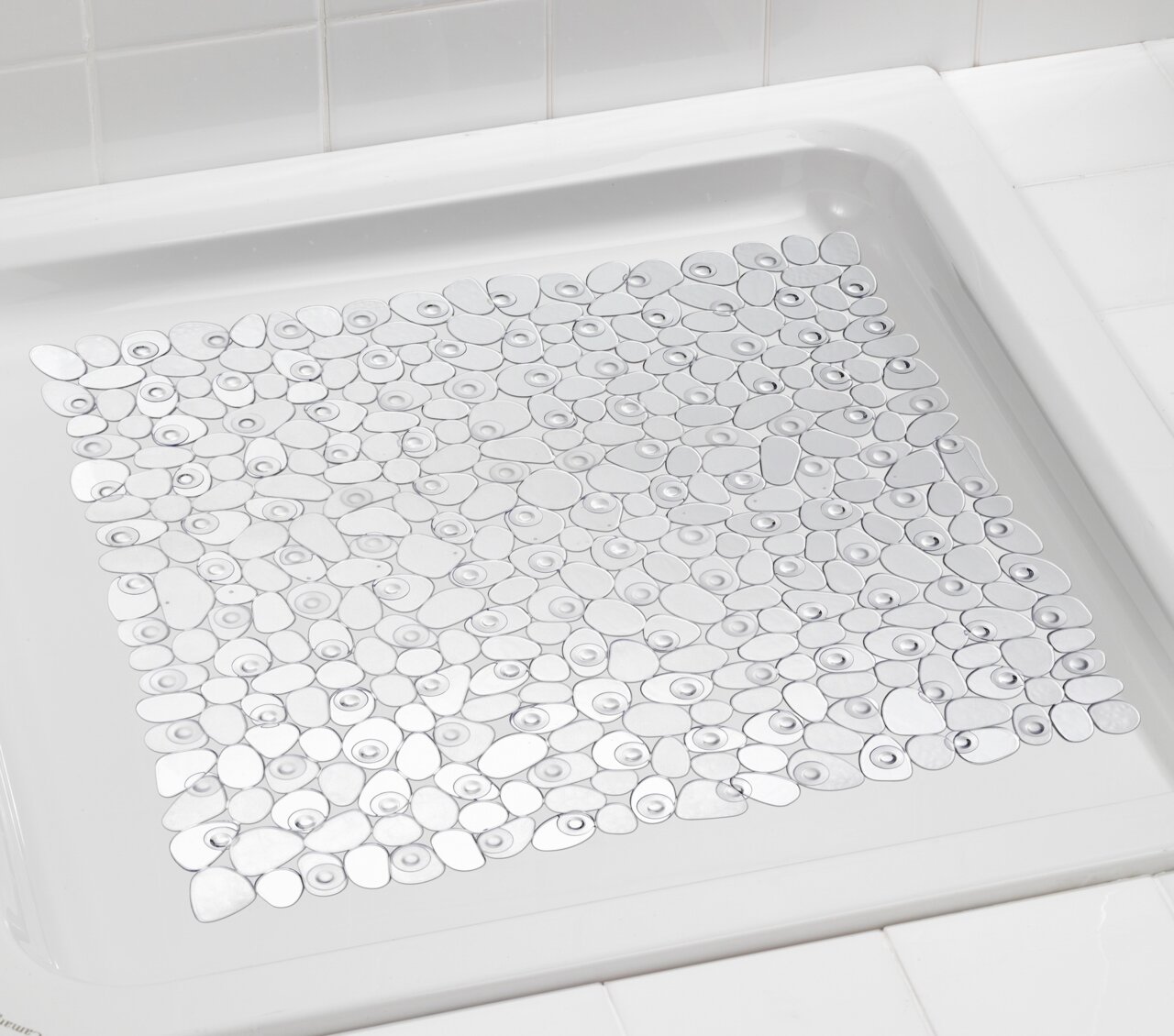 Transparente Duscheinlage mit rutschfestem Design in einer weißen Duschwanne, von oben betrachtet.