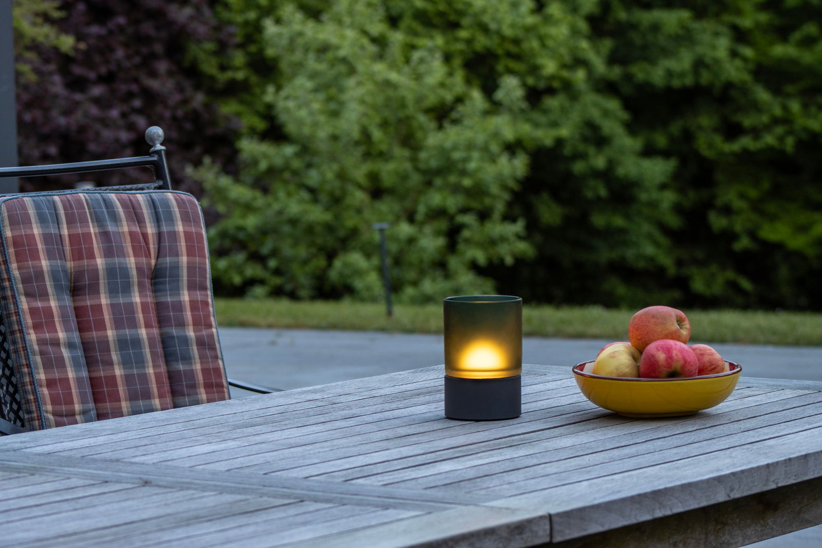 Fischer & Honsel ARIVA PRO windlicht op batterijen Akku-Windlicht auf einem Holztisch im Freien, neben einer Schale mit Äpfeln, aus seitlicher Perspektive fotografiert.