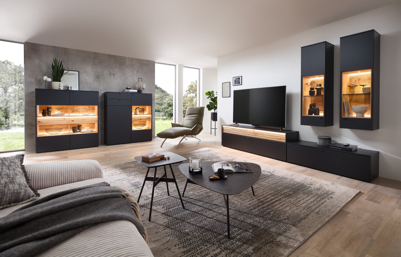 Venjakob Wandkombination LUMEA Moderne Wohnzimmer-Wandkombination in dunklem Design mit beleuchteten Vitrinen, TV-Schrank und dekorativen Elementen, seitliche Perspektive.
