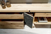 Wohnwand aus hellem Holz mit offenen Schubladen und Fächern, von oben fotografiert.