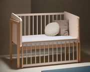 Anstellbett aus Holz mit weißen Gitterstäben, seitliche Perspektive, zwei Kissen auf der Matratze.