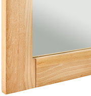 Nahaufnahme eines Spiegels mit einem Rahmen aus hellem Holz, perspektivisch von der Seite aufgenommen.