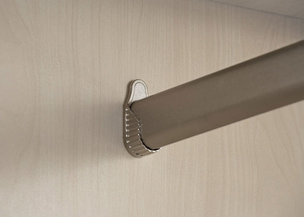 Nahaufnahme einer Kleiderstange in einem Drehtürenschrank, montiert an einer hellen Holzplatte.