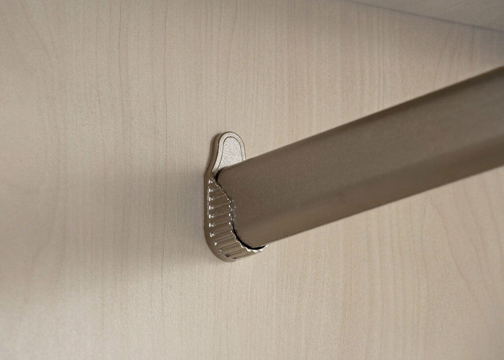 Nahaufnahme einer Kleiderstange in einem Drehtürenschrank, montiert an einer hellen Holzplatte.