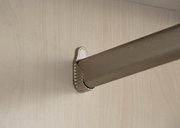 Nahaufnahme einer Kleiderstange in einem Drehtürenschrank, montiert an einer hellen Holzplatte.