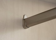 Nahaufnahme einer Kleiderstange in einem Drehtürenschrank, montiert an einer hellen Holzplatte.