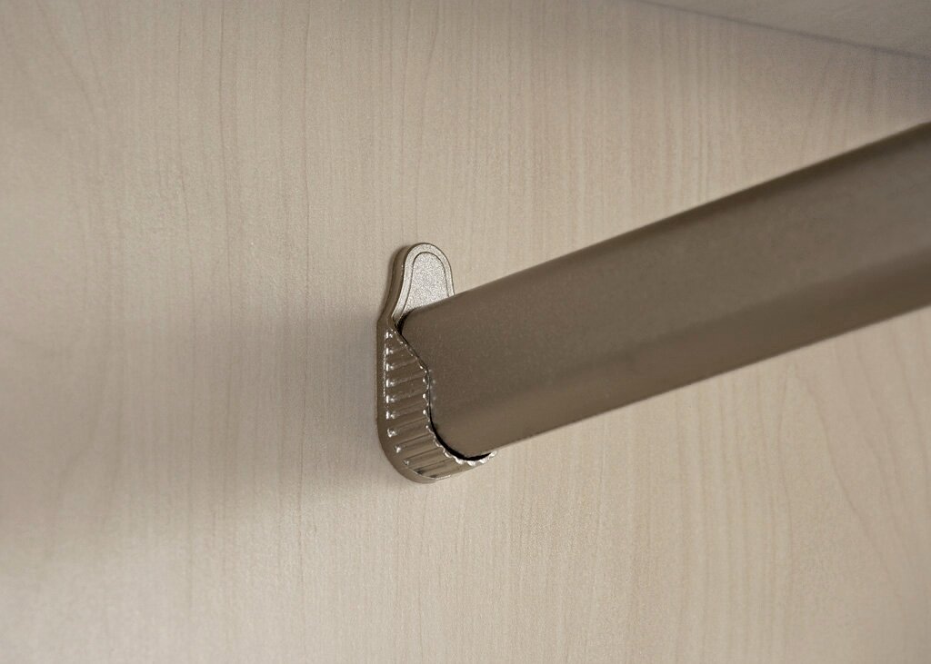 Close-up van een kledingstang in een kast met draaideuren, bevestigd aan een lichte houten plaat.