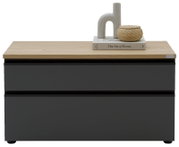 Frontansicht auf eine moderne Kommode mit mattschwarzer Front und heller Holzplatte, oben dekoriert mit Buch, Keramikvase und geflochtenem Korb vor weißem Hintergrund.