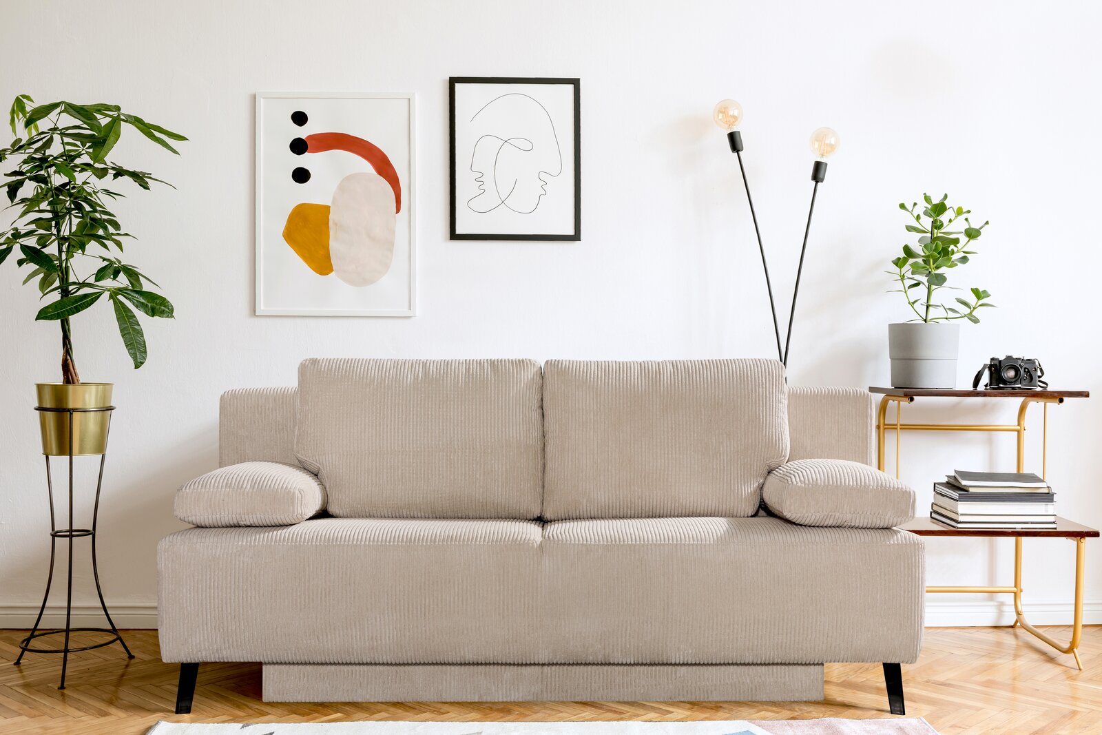 Novel Schlafsofa SPICY Beige Querschläfer-Sofa in einem modernen Wohnzimmer, frontal fotografiert. Umgeben von Pflanzen, Kunstwerken und einem Beistelltisch.